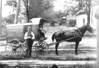 Baker and cart at rail crossing on Main St.